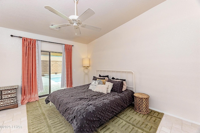 bedroom with baseboards, a ceiling fan, stone finish floor, access to outside, and vaulted ceiling