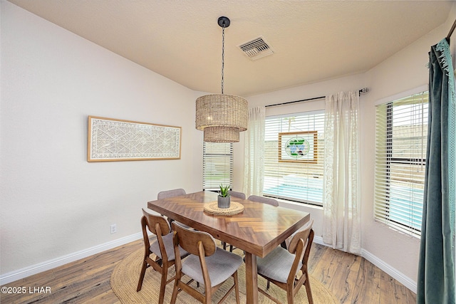 dining area with baseboards, visible vents, and light wood finished floors