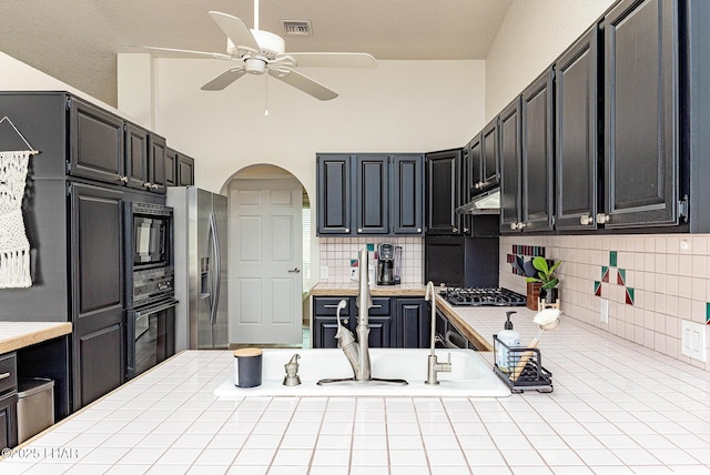 kitchen with visible vents, arched walkways, oven, gas stovetop, and stainless steel refrigerator with ice dispenser