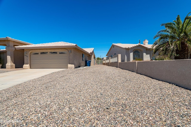 2335 Palo Verde Blvd N, Lake Havasu City, AZ 86404 - view of side of home with fence, stucco siding, a tiled roof, and an attached garage