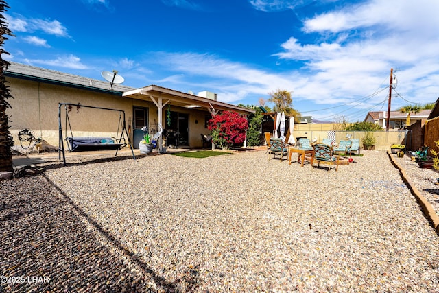 back of house featuring a patio area, a trampoline, fence, and stucco siding