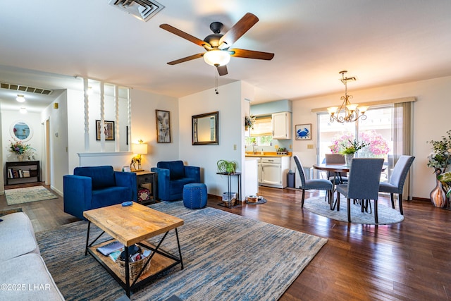 living room with baseboards, visible vents, dark wood finished floors, and ceiling fan with notable chandelier