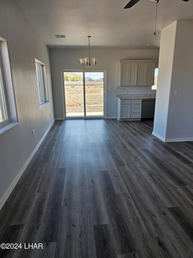 unfurnished living room featuring ceiling fan with notable chandelier and dark hardwood / wood-style flooring