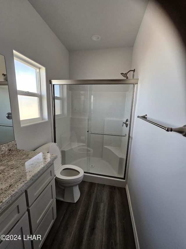 bathroom featuring toilet, vanity, a shower with door, and hardwood / wood-style floors