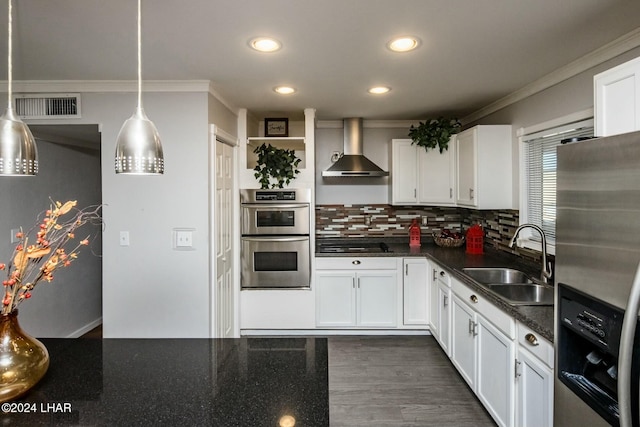 kitchen featuring appliances with stainless steel finishes, decorative light fixtures, sink, white cabinets, and wall chimney exhaust hood