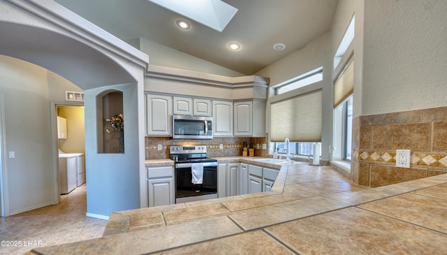 3000 Mirage Dr, Lake Havasu City, AZ 86404 - kitchen featuring appliances with stainless steel finishes, a sink, washing machine and clothes dryer, a skylight, and plenty of natural light