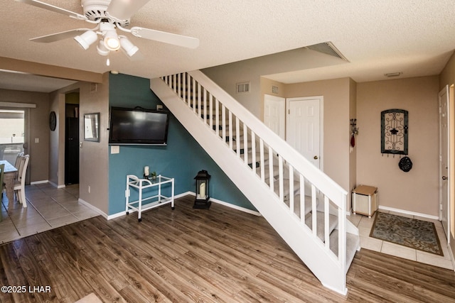 staircase featuring baseboards, a textured ceiling, and wood finished floors