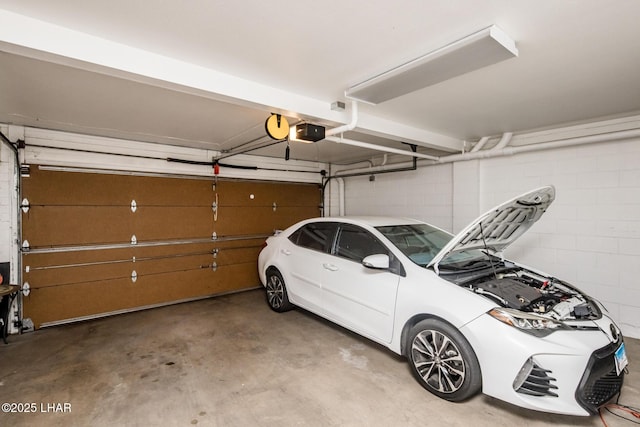 parking garage featuring a garage door opener and concrete block wall