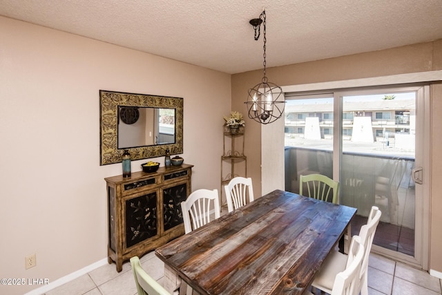 dining area featuring light tile patterned floors, a chandelier, a textured ceiling, and baseboards