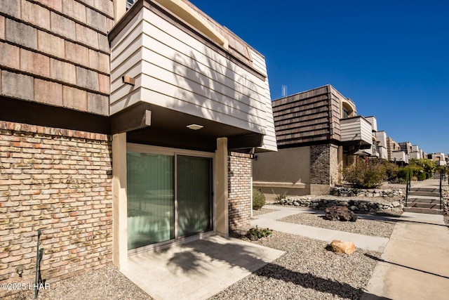 doorway to property with mansard roof and brick siding