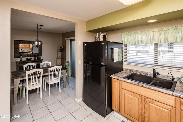 kitchen with a sink, light tile patterned floors, light countertops, and freestanding refrigerator