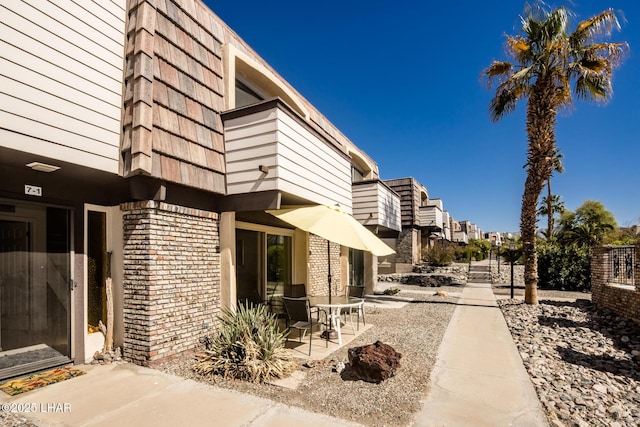 view of property exterior featuring brick siding and a patio area