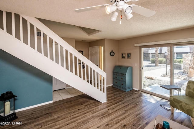 foyer entrance with stairway, wood finished floors, baseboards, ceiling fan, and a textured ceiling