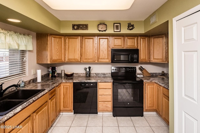 kitchen featuring dark countertops, visible vents, light tile patterned floors, black appliances, and a sink