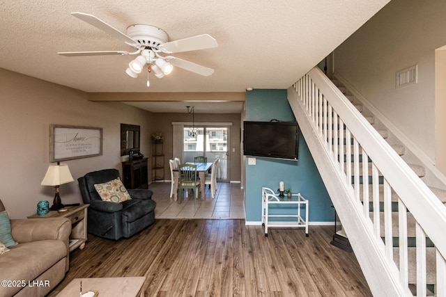 living room with stairway, wood finished floors, visible vents, and a textured ceiling