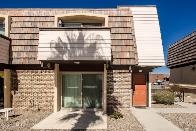 exterior space featuring mansard roof, brick siding, and a balcony