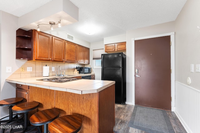 276 Lake Havasu Ave S Unit C19, Lake Havasu City, AZ 86403 - kitchen with visible vents, tile countertops, brown cabinets, a peninsula, and black appliances