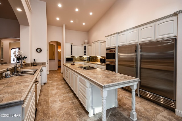 kitchen with high vaulted ceiling, sink, white cabinets, kitchen peninsula, and stainless steel appliances