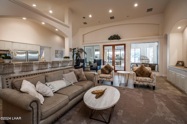 carpeted living room with a towering ceiling and french doors