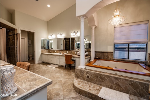 bathroom featuring toilet, ornate columns, high vaulted ceiling, vanity, and tiled bath