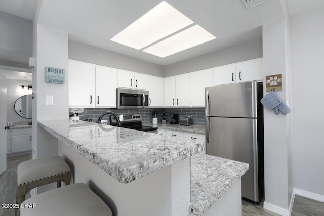1650 Smoketree Ave S Unit 135, Avenue, Lake Havasu City, AZ 86403 - kitchen featuring stainless steel appliances, a peninsula, a breakfast bar, decorative backsplash, and white cabinets