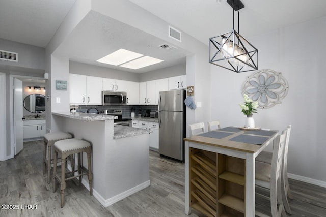 1650 Smoketree Ave S Unit 135, Avenue, Lake Havasu City, AZ 86403 - kitchen featuring appliances with stainless steel finishes, a peninsula, light wood finished floors, and white cabinets