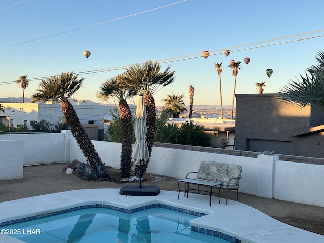 pool at dusk with a hot tub