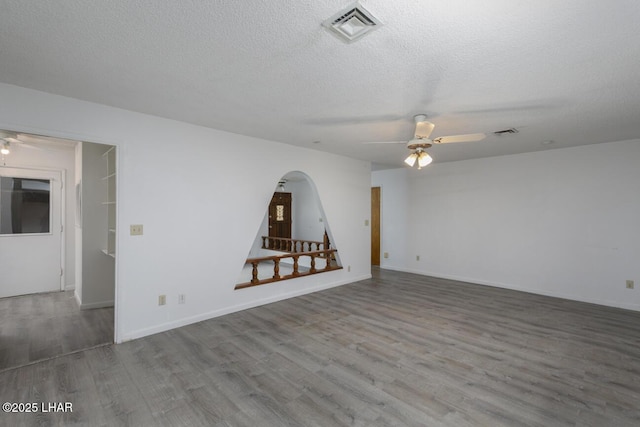 empty room with visible vents, ceiling fan, and wood finished floors