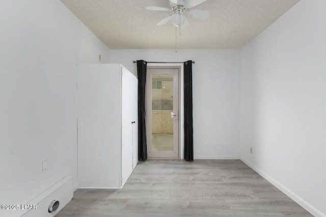 unfurnished room with baseboards, a textured ceiling, ceiling fan, and wood finished floors