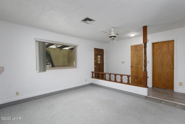 unfurnished room with baseboards, a ceiling fan, visible vents, and a textured ceiling