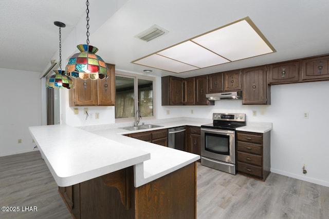 kitchen featuring visible vents, under cabinet range hood, a peninsula, stainless steel appliances, and a sink