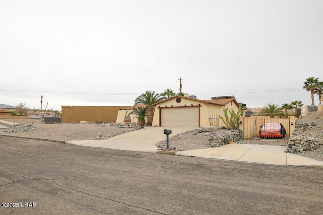 view of front of property with fence, concrete driveway, stucco siding, a garage, and a gate