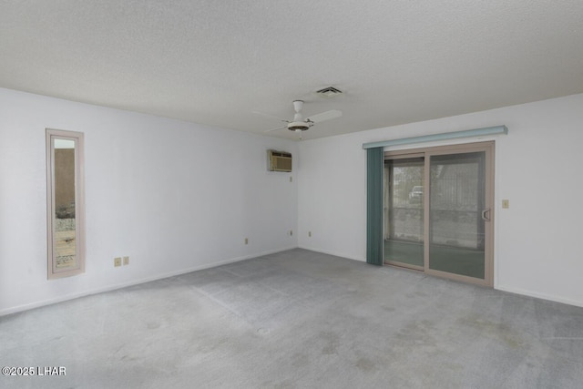 empty room with carpet, a ceiling fan, visible vents, a wall mounted air conditioner, and a textured ceiling