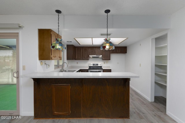 kitchen featuring visible vents, stainless steel range with electric stovetop, a sink, under cabinet range hood, and light countertops