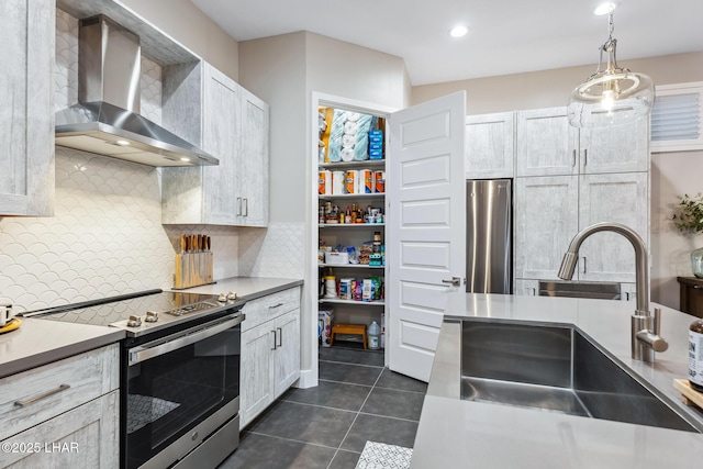 kitchen featuring sink, stainless steel appliances, white cabinets, decorative light fixtures, and wall chimney exhaust hood