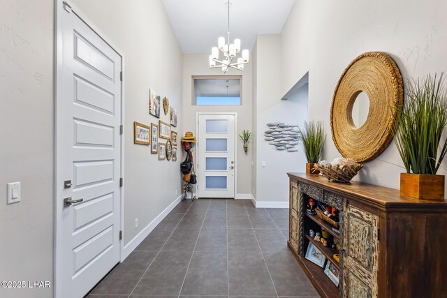 foyer entrance with dark tile patterned floors and a chandelier