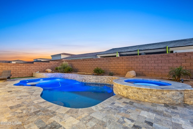 pool at dusk with a patio and an in ground hot tub