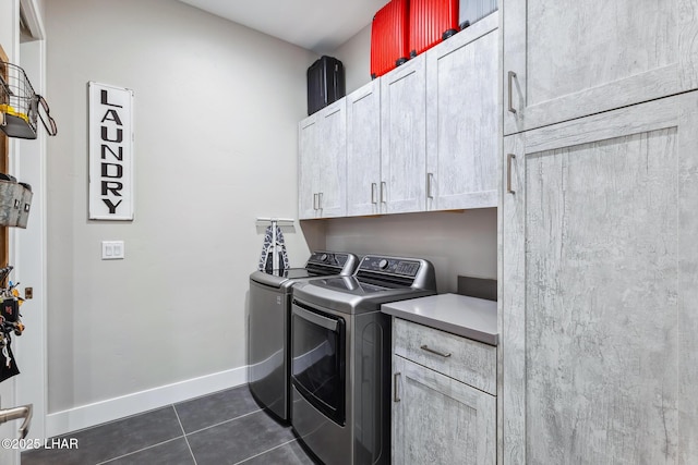 washroom featuring cabinets, dark tile patterned floors, and washing machine and clothes dryer