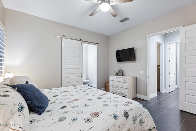 tiled bedroom with ceiling fan, connected bathroom, and a barn door