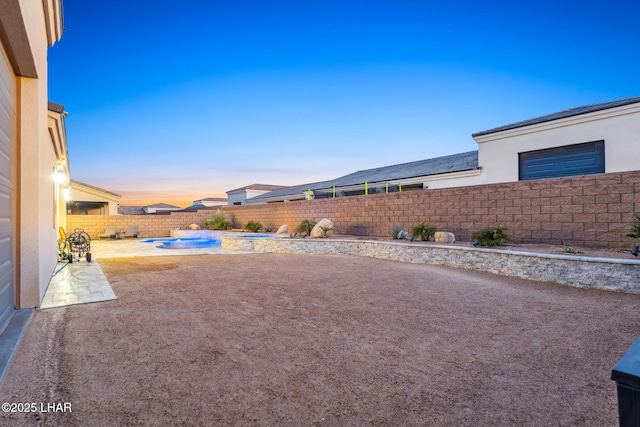 yard at dusk featuring a fenced in pool and a patio