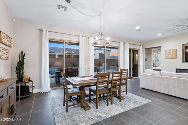 tiled dining room with ceiling fan with notable chandelier