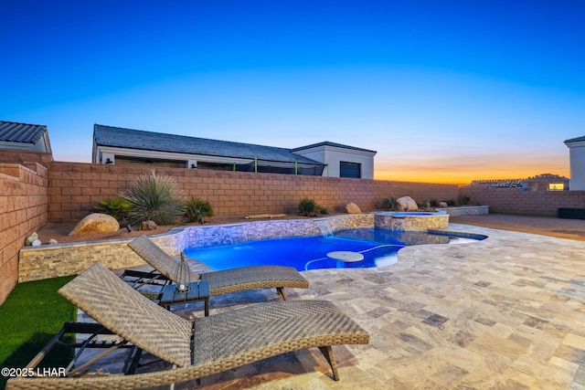 pool at dusk featuring an in ground hot tub, pool water feature, and a patio area