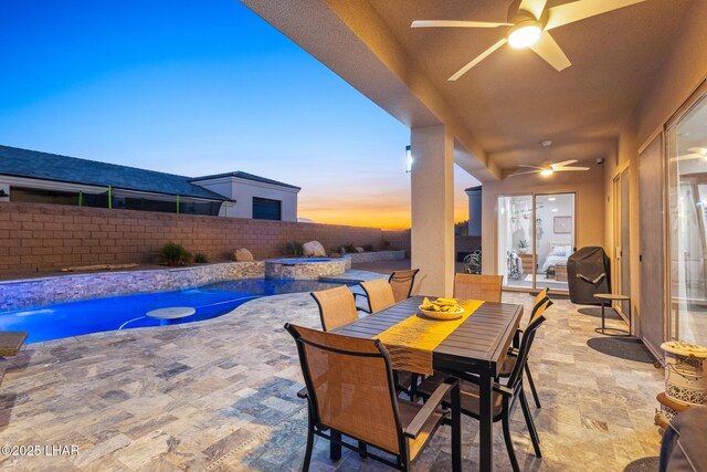 patio terrace at dusk featuring a swimming pool with hot tub, pool water feature, and ceiling fan