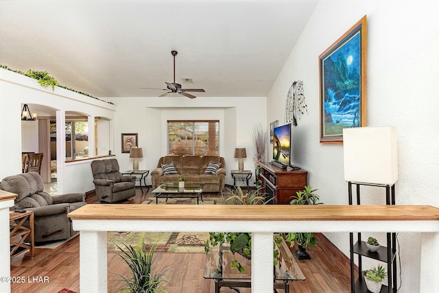 living room featuring ceiling fan with notable chandelier and hardwood / wood-style floors