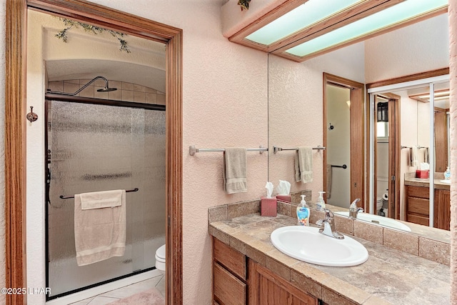 bathroom featuring walk in shower, vanity, tile patterned floors, and toilet