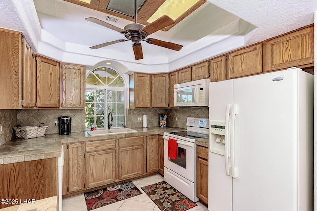 kitchen with tasteful backsplash, white appliances, sink, and light tile patterned floors