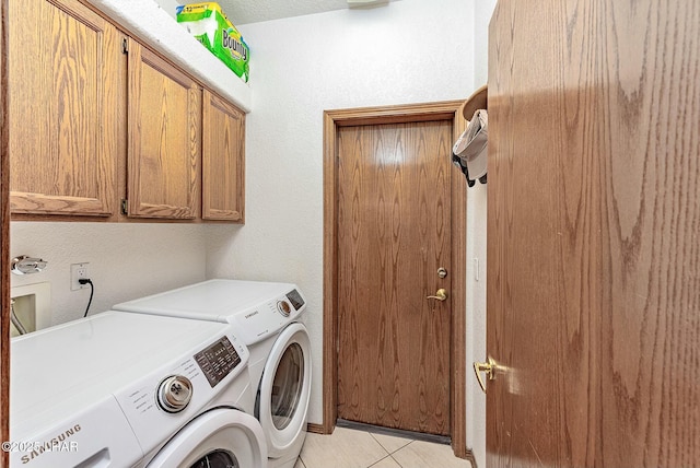 washroom featuring cabinets, light tile patterned flooring, and washer and clothes dryer