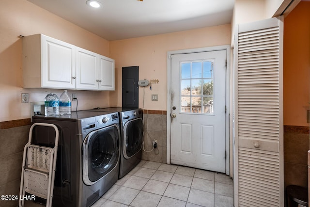 laundry room with tile walls, electric panel, cabinets, light tile patterned flooring, and separate washer and dryer