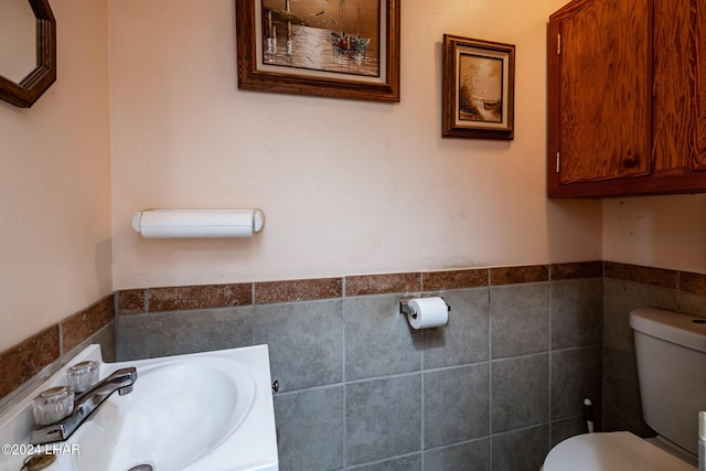 bathroom with sink, tile walls, and toilet