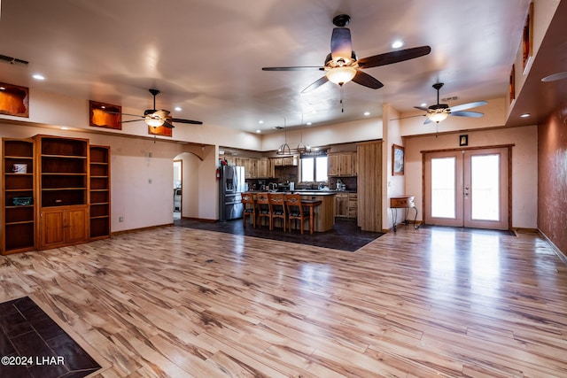 unfurnished living room with french doors, a wealth of natural light, and light hardwood / wood-style flooring